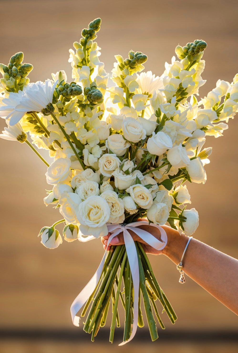 Ramo de novia con flores blancas y listones en tonos suaves